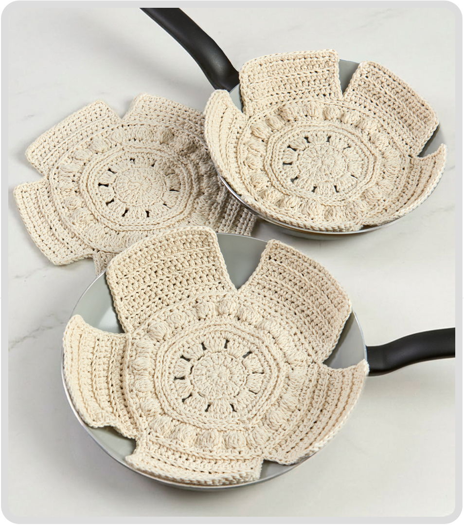Three decorative, crocheted pot holders in various sizes on a white surface.