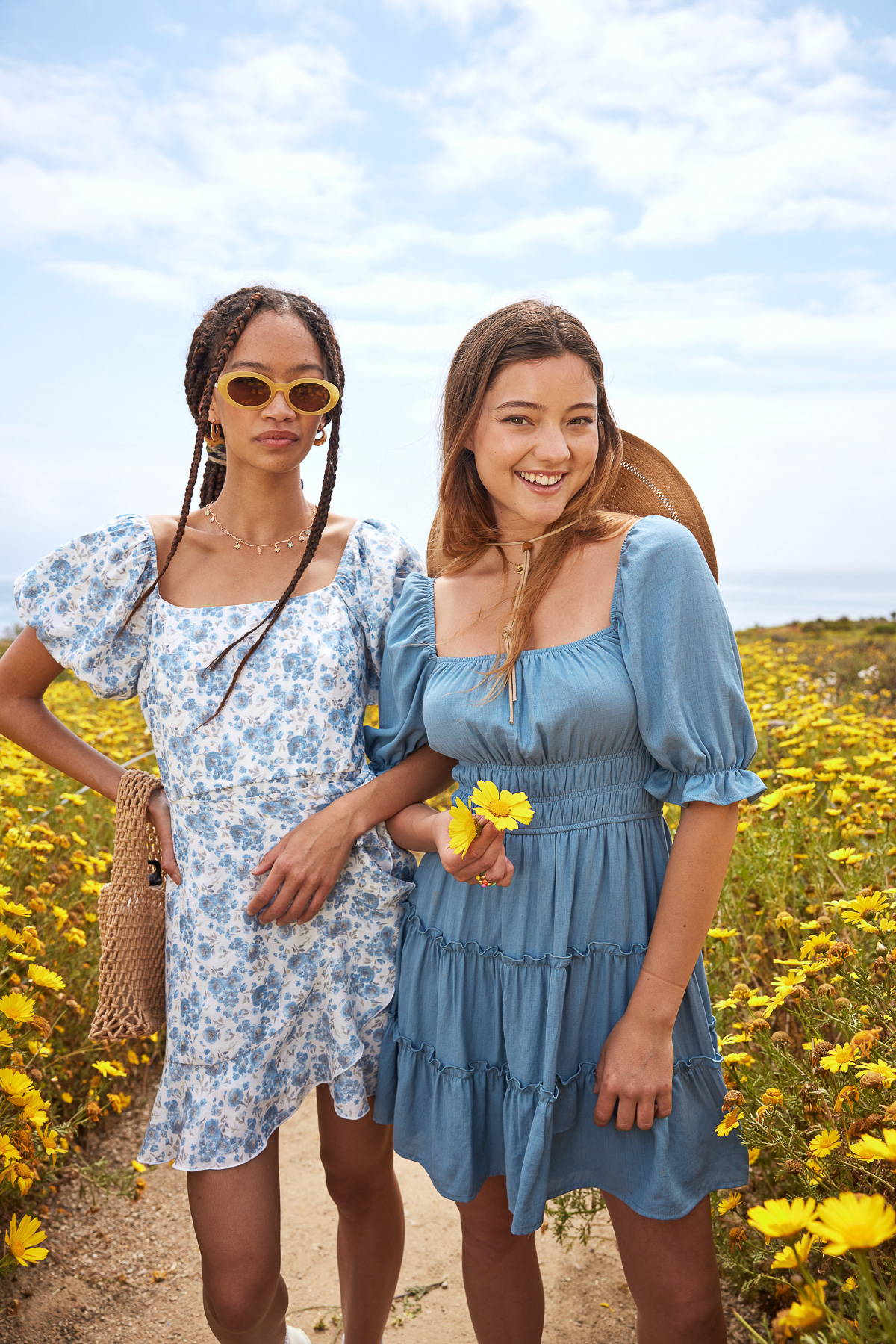 Trixxi sun-kissed summer lookbook, 2 girls in yellow floral field in blue printed floral mini dress and blue tiered dress.