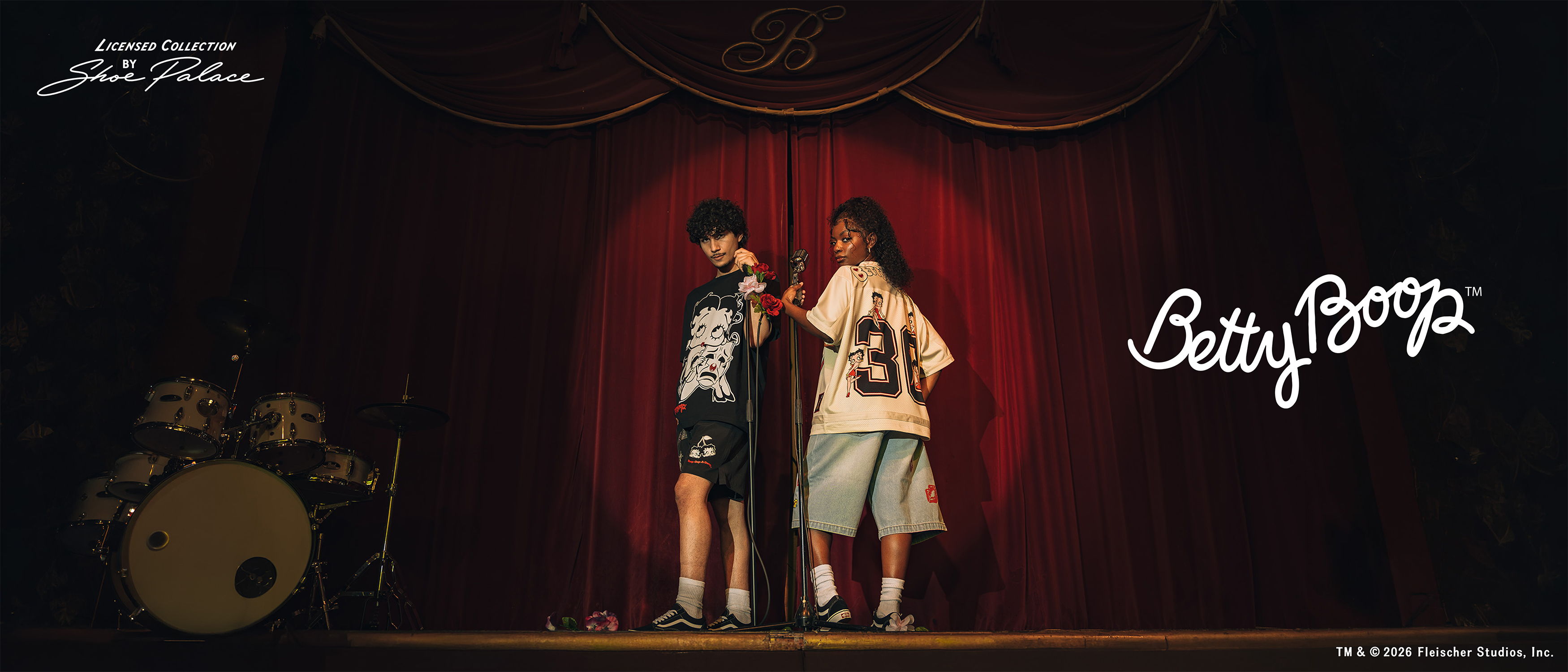 Two children on stage with a red curtain backdrop.