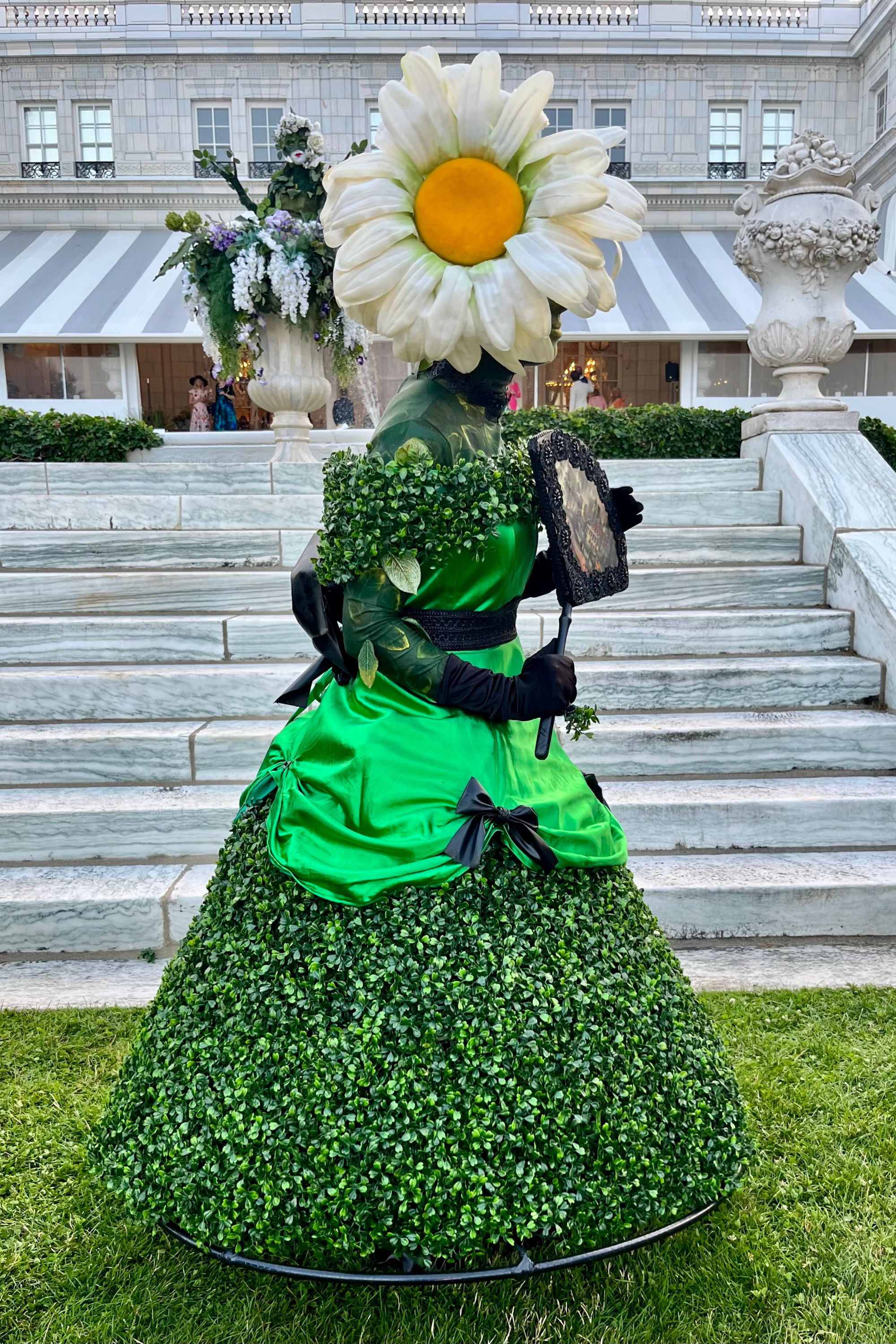 A person in a floral costume with a green dress and daisy headpiece a the Newport Flower Show in Rhode Island at The Breakers Mansion