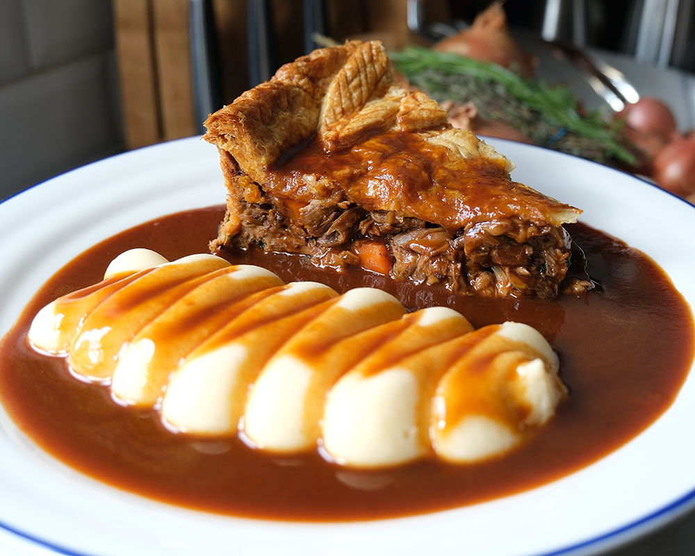 Lamb shank pie served with mashed potatoes and gravy.