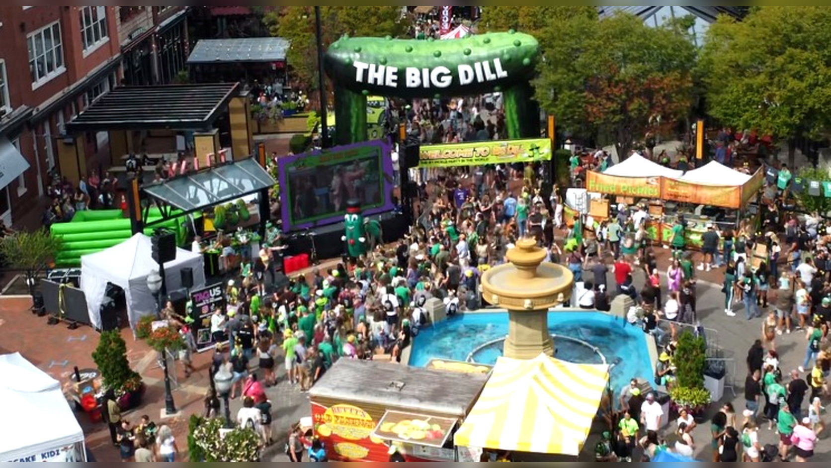 Crowd gathering at a festive outdoor event with colorful tents and decorations.