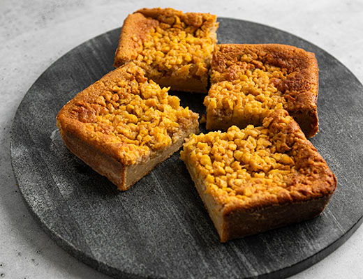 Slices of cake with a crumbly topping on a dark serving platter.