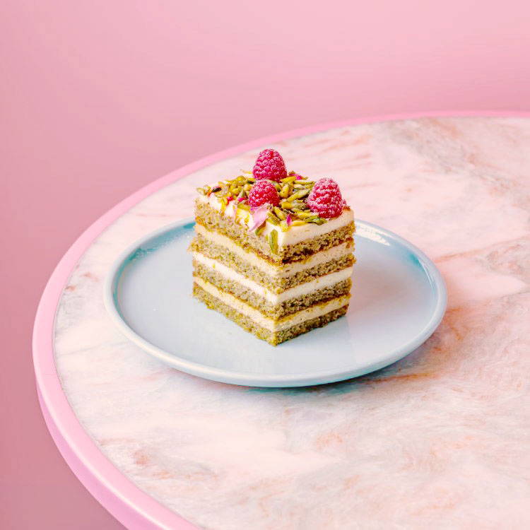 Pistachio Cake stacked with pistachio cream and fresh raspberries on top