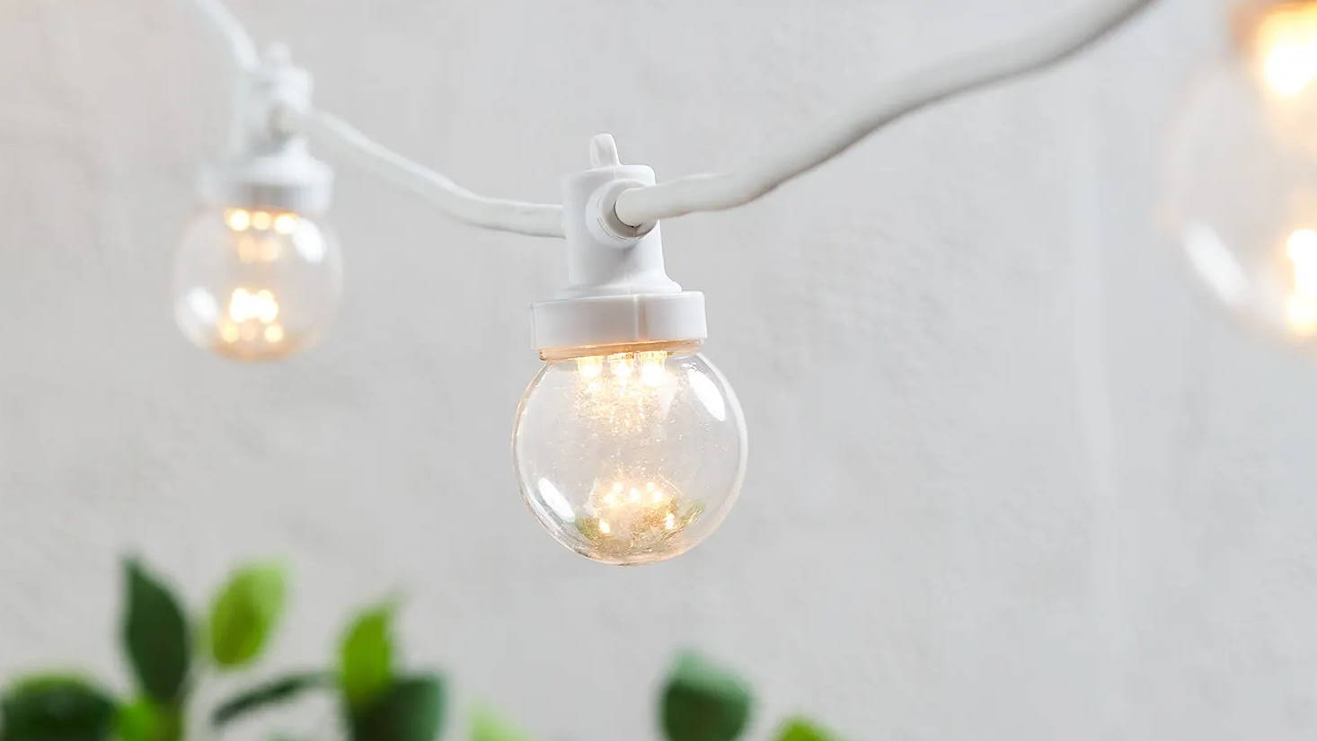 Close up image of white festoon lights in a garden setting