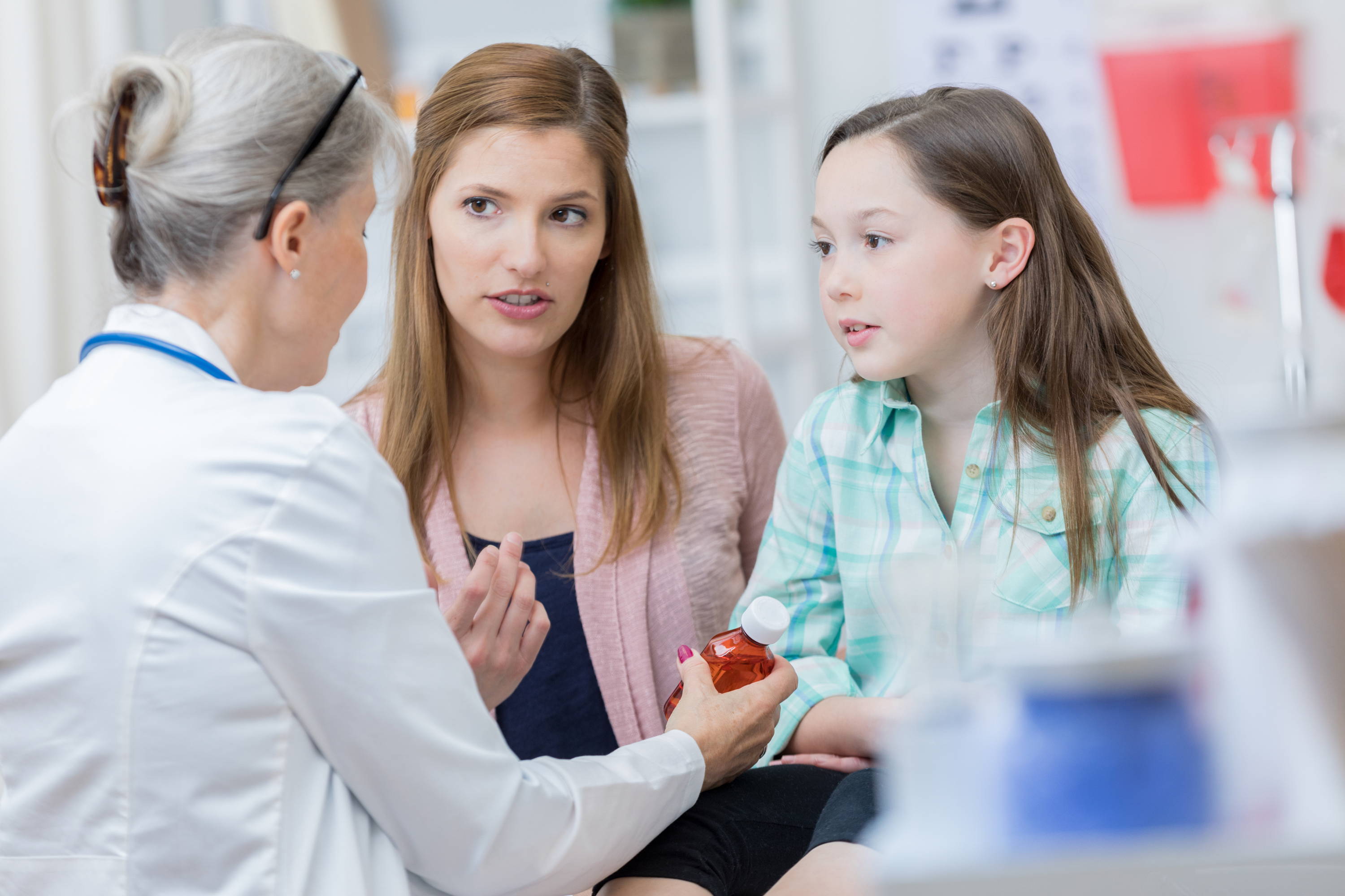 Pharmacist explaining to a mother and her young daughter when and how to take her allergy relief medication