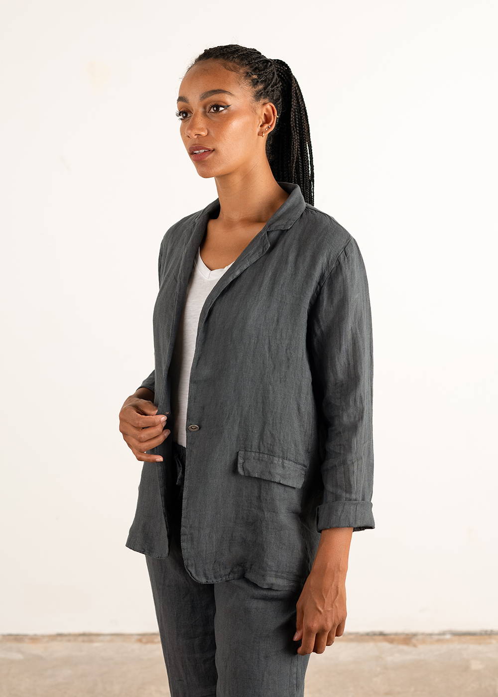 A model wearing a dark grey linen jacket over a white top  and matching trousers