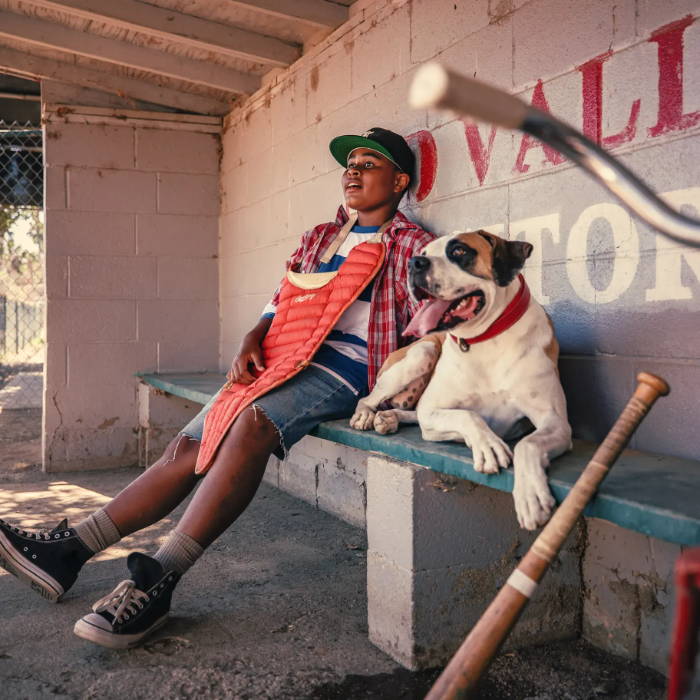 young kid and his dog sitting in baseball dugout