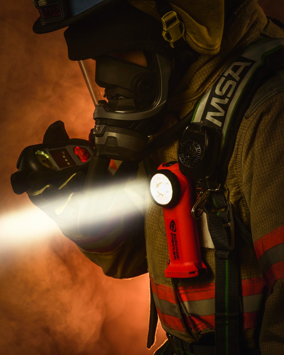 Firefighter wearing a mask and holding a flashlight in a smoky environment.