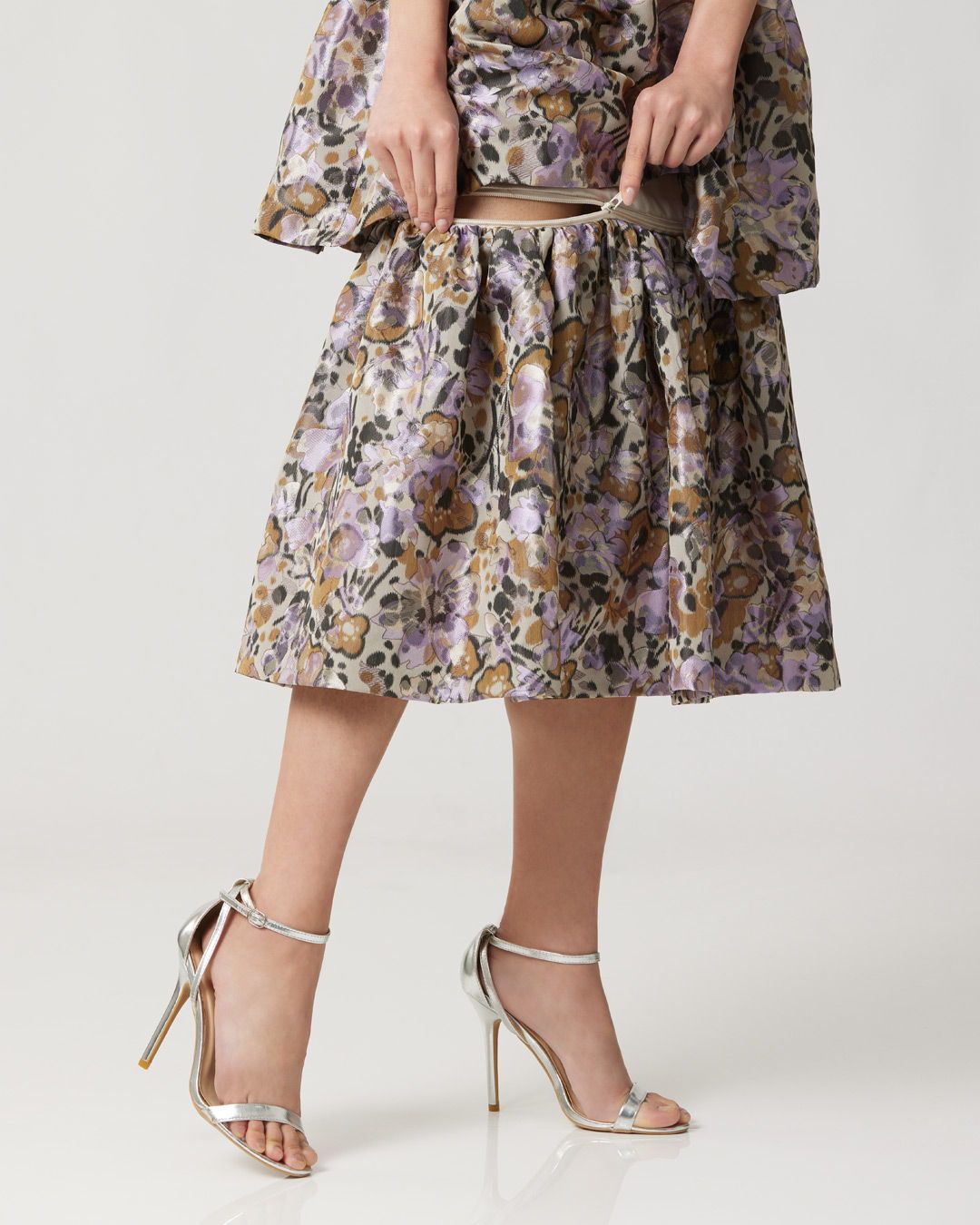 Model wearing a floral patterned outfit with silver high-heeled sandals.