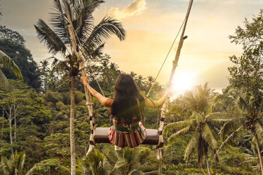 Person on a rope swing overlooking a jungle valley at sunset