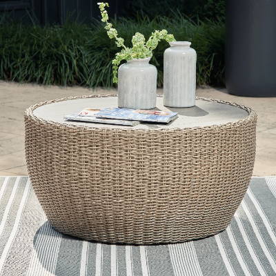 A collection of grey vases and magazines sit atop a wicker outdoor table.