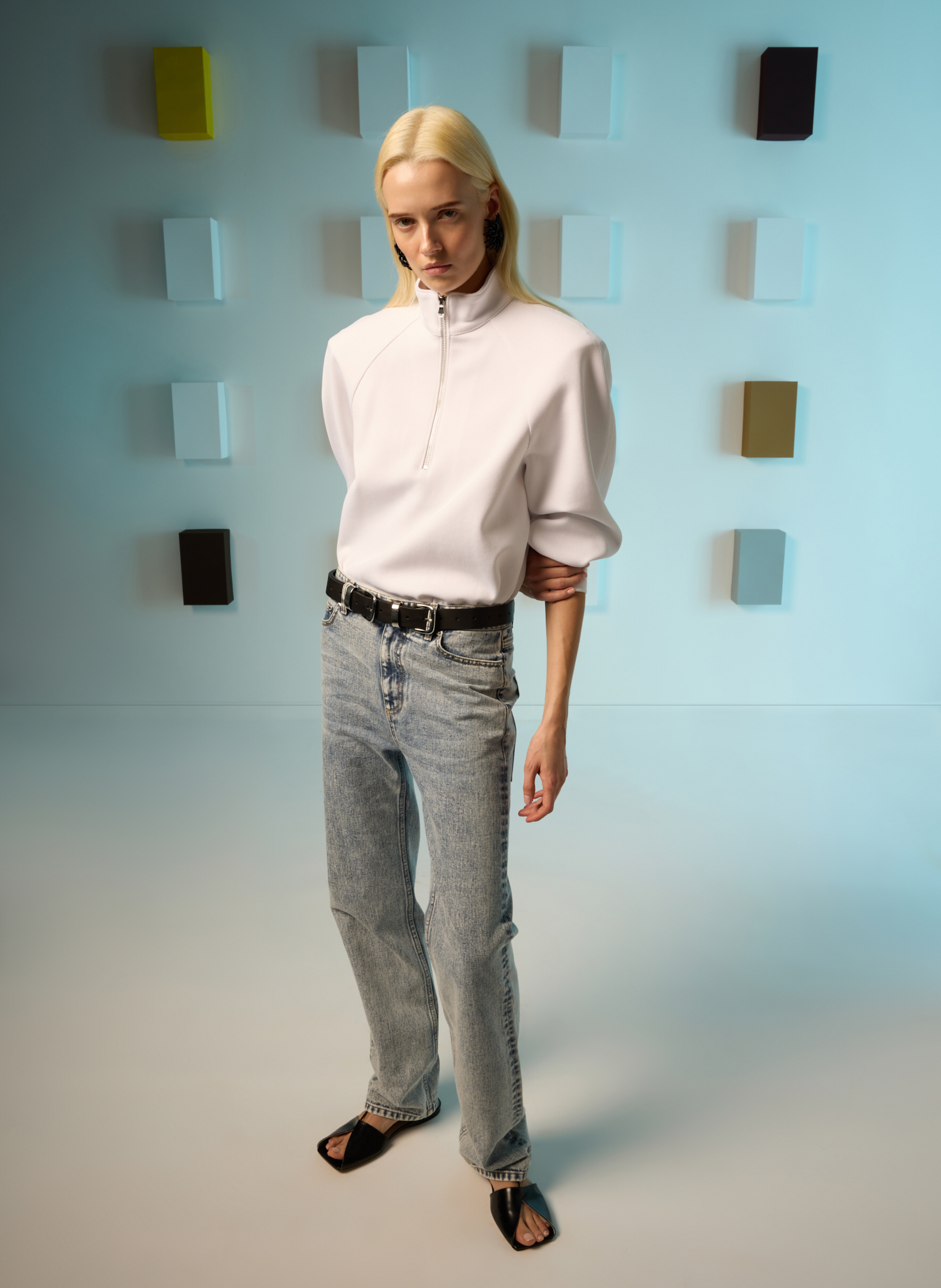 Model in a stylish outfit poses against a minimalist background.