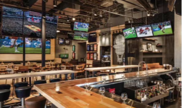 Modern sports bar with multiple TVs and a wooden counter.