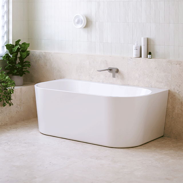 Modern white Caroma Urbane bathtub in a stylish bathroom setting with plants.