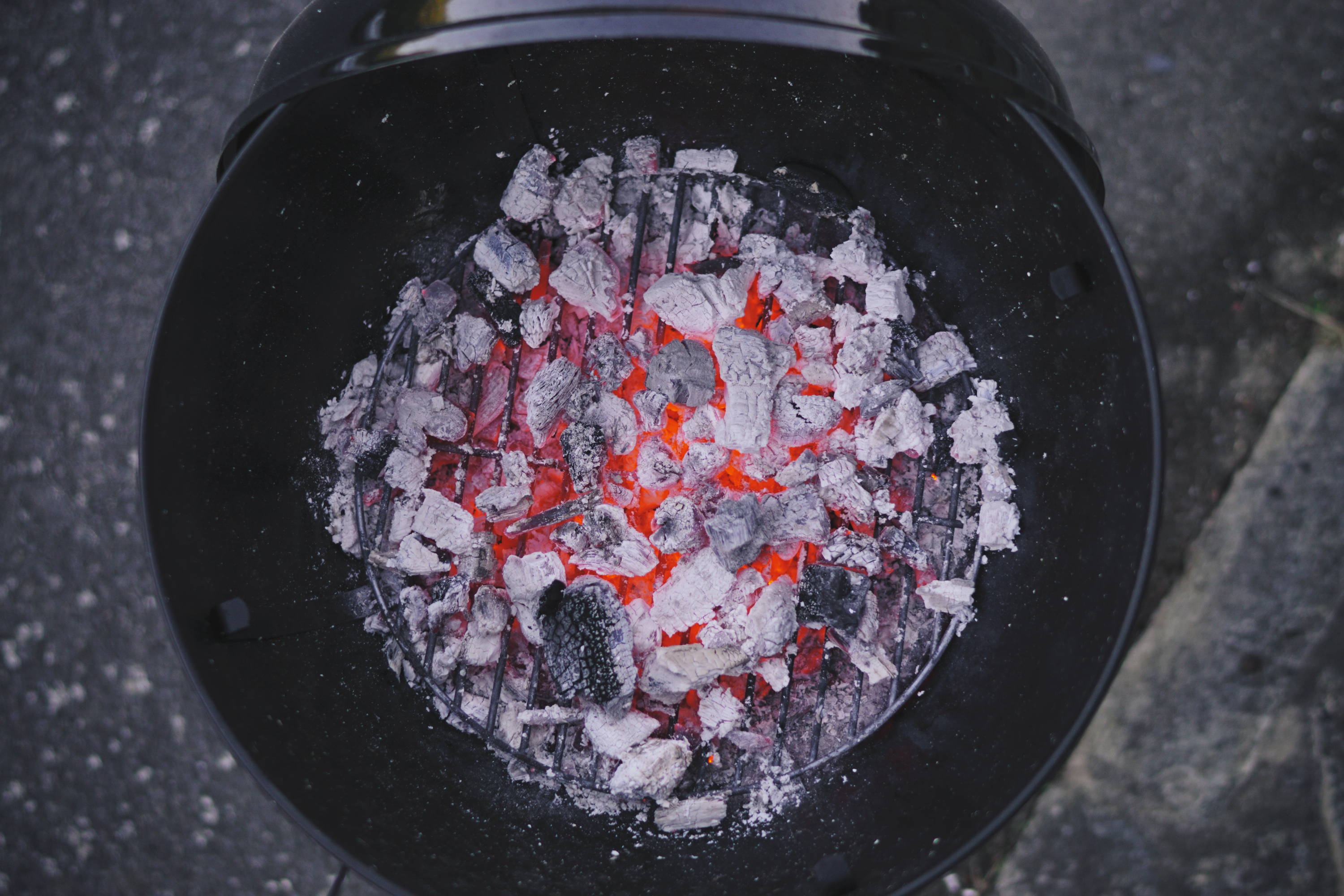 Mastering Your Charcoal Grill. Ashy charcoal glows at bottom of grill.