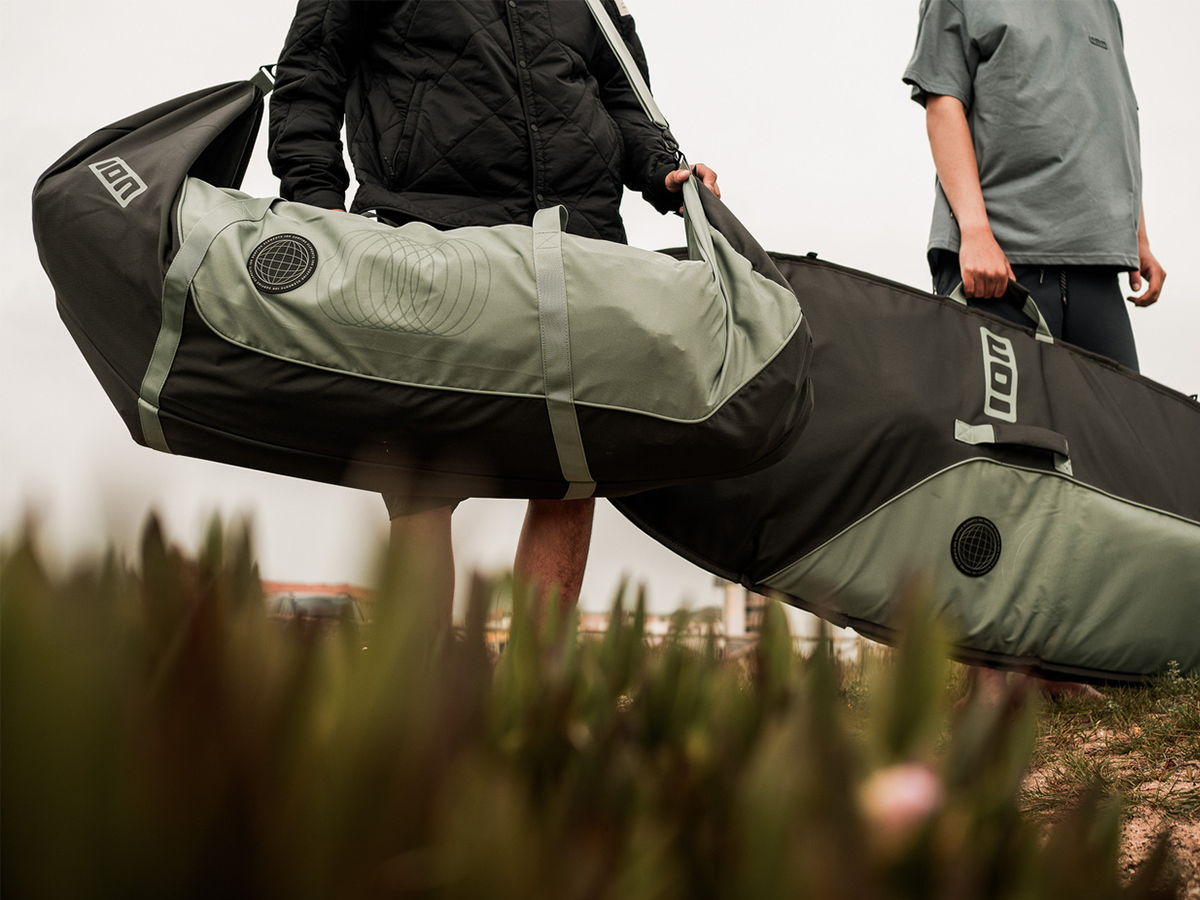 Two people carrying a large bag near grass.