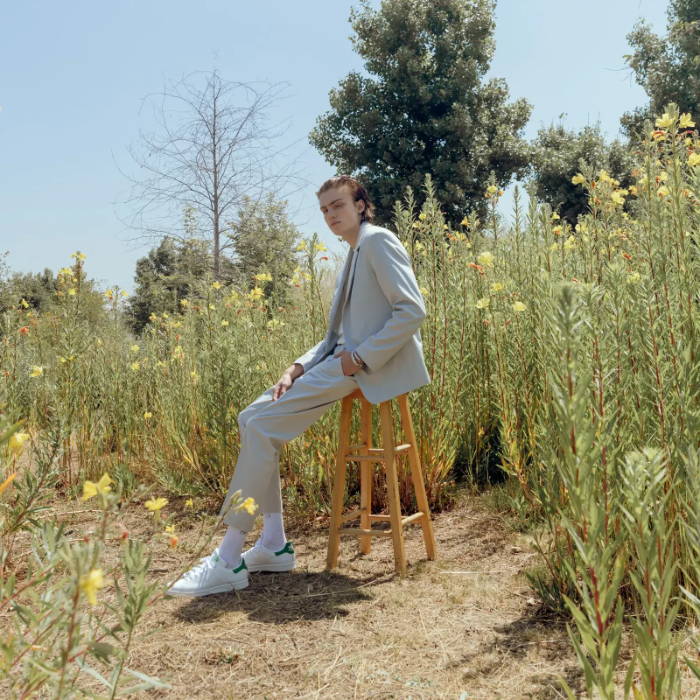 made model in gray suit wearing white adidas stan smith in flower field