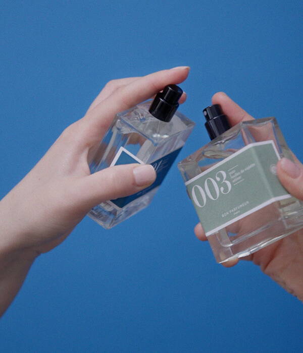 A styled image of two hands holding Bon Parfumeur fragrances.