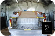 Technicians covering a truck to protect it from spray-on bedliner overspray