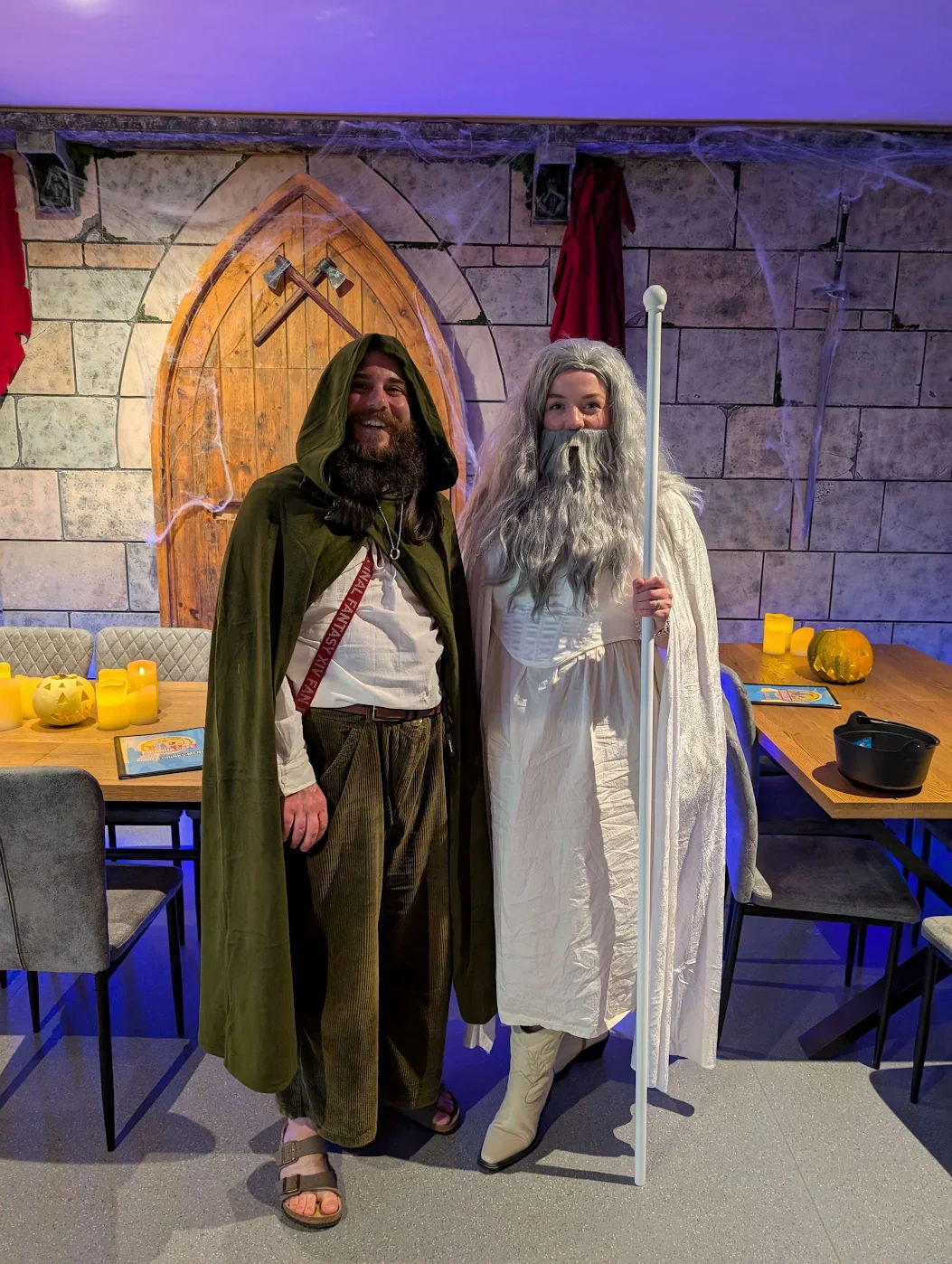 Two people in fantasy costumes standing in a themed room.