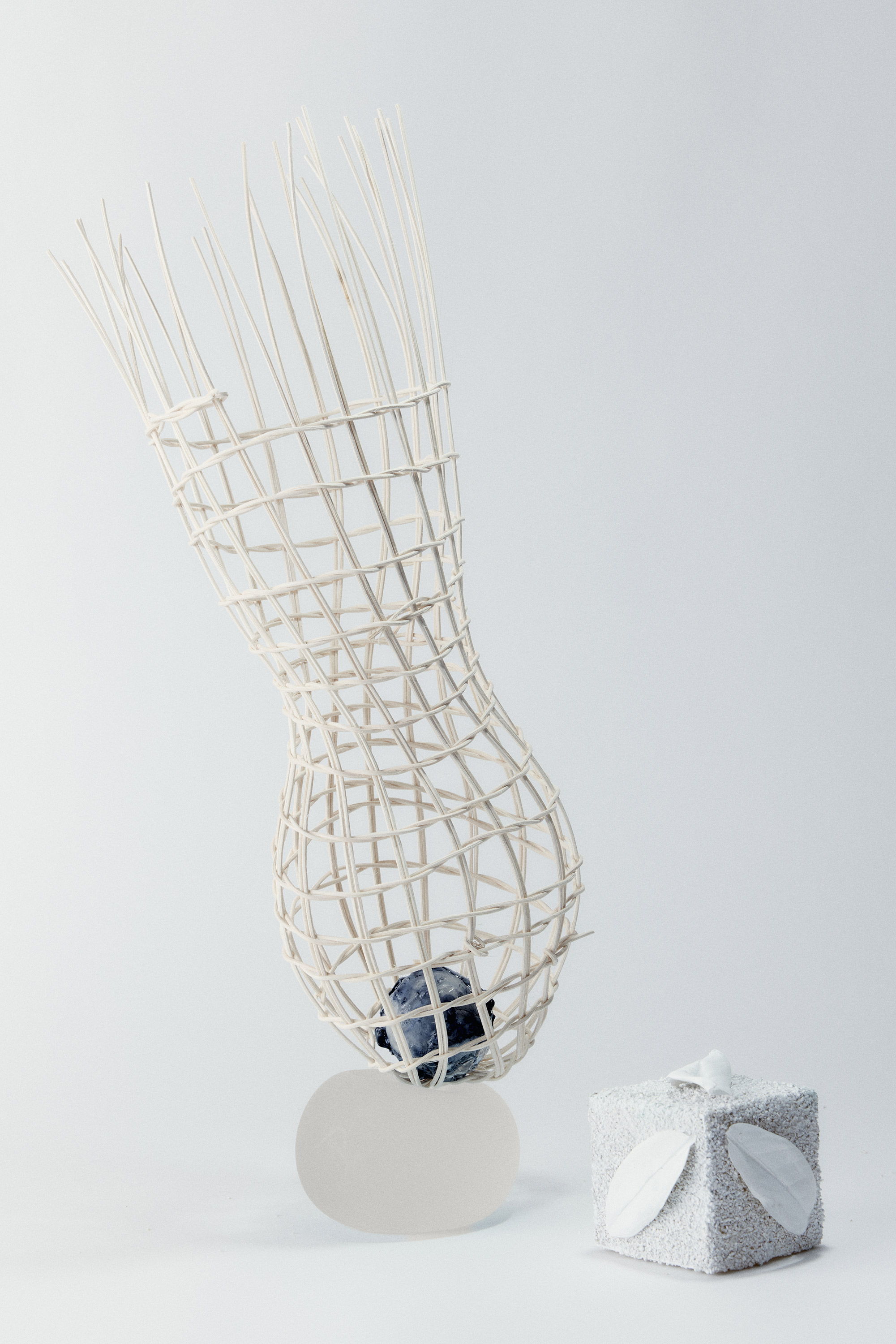 A sculptural piece with woven elements and a small gift box.