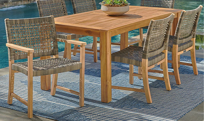 Wooden dining table with six chairs beside a pool.