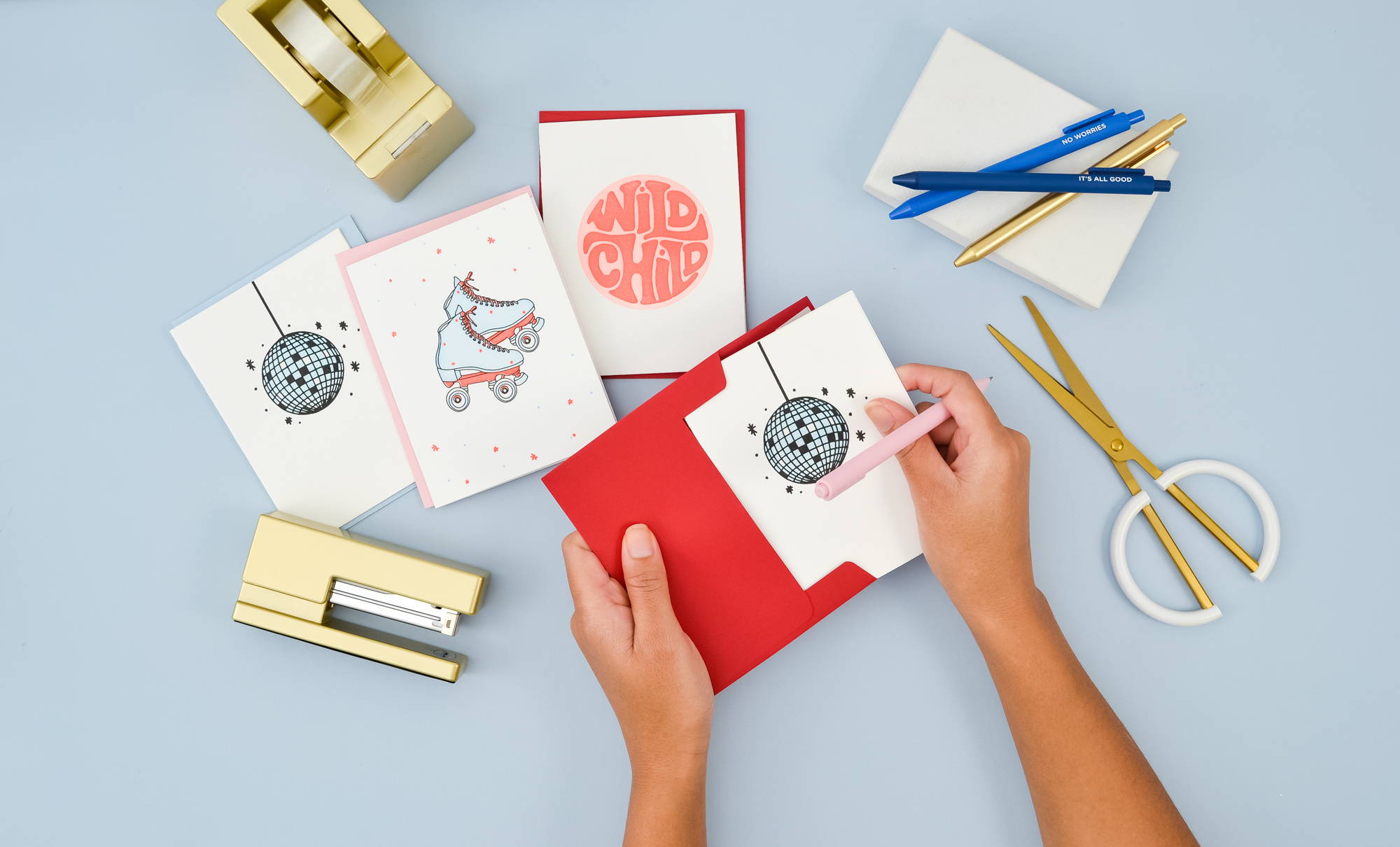 Fun gold stapler and tape dispenser with a mix of letter press cards featuring roller skates, disco balls, and a wild child card