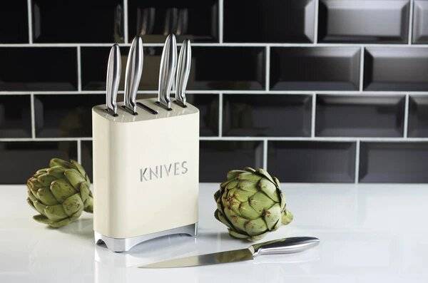 A knife block on the kitchen side. One of the knives is out of the block and on the kitchen top.