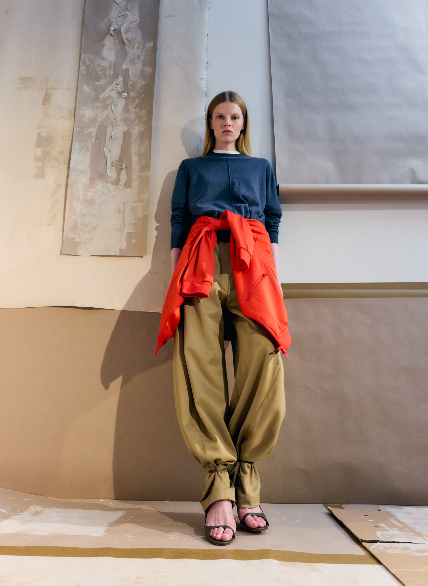 A model in casual attire with a red sweater and loose pants.