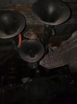 Undercarriage view of three black trumpet air horns mounted to vehicle frame with red air line
