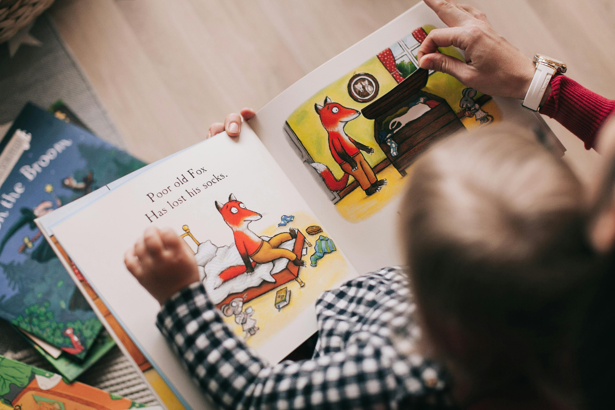 Child reading a colorful storybook featuring a fox illustration.