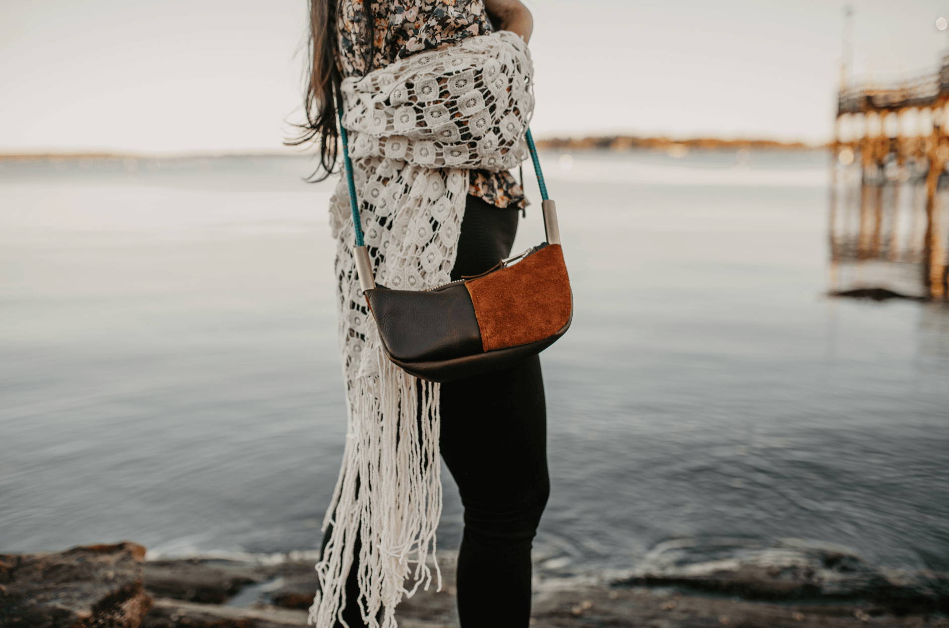 woman wearing brown leather crossbody with teal dockline on the harbor