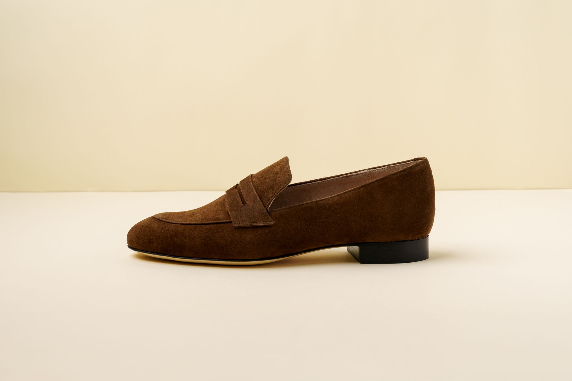 Brown suede loafer shoe on a neutral background.