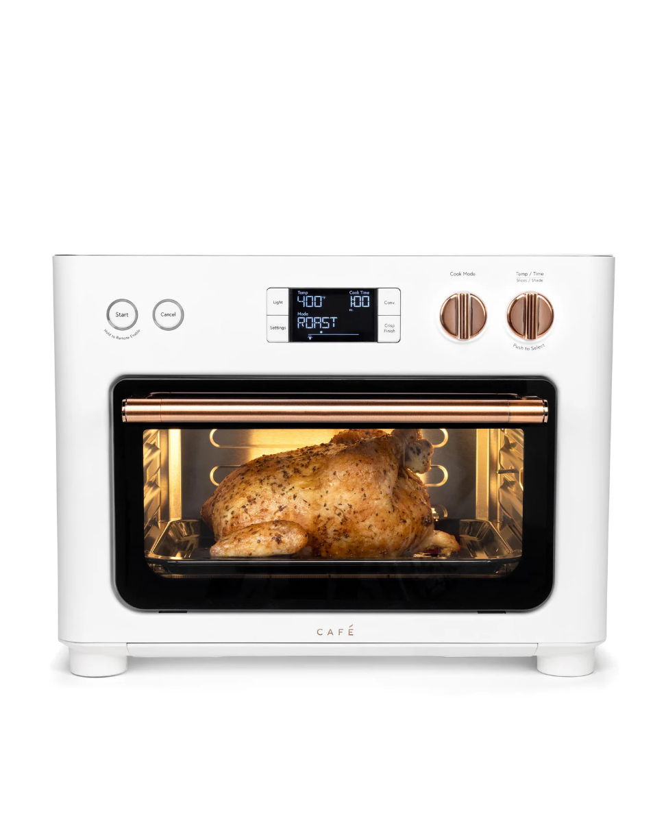 A white countertop oven with a roasted chicken inside.