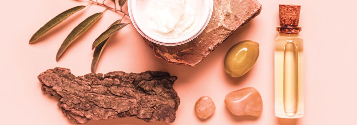 Natural skincare products arranged on a pastel background with stones and leaves.