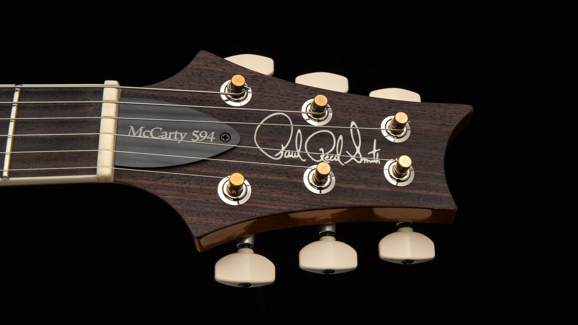 PRS guitar headstock with tuning pegs and signature.
