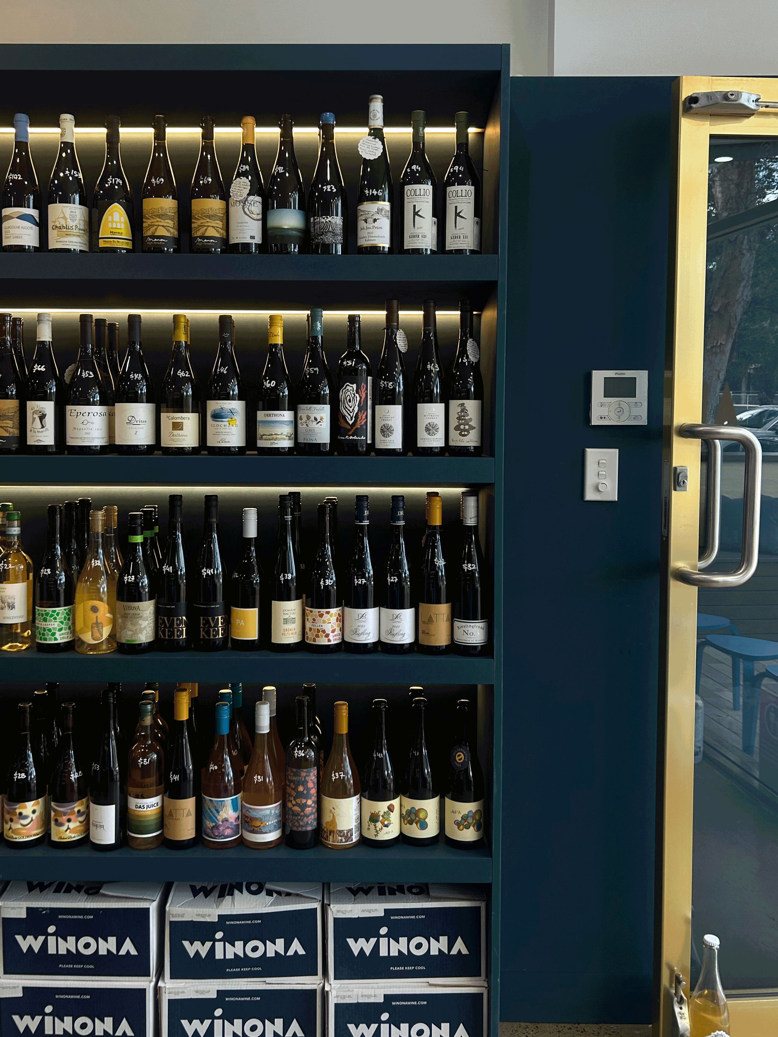 Shelves filled with various bottles of wine and a glass door.