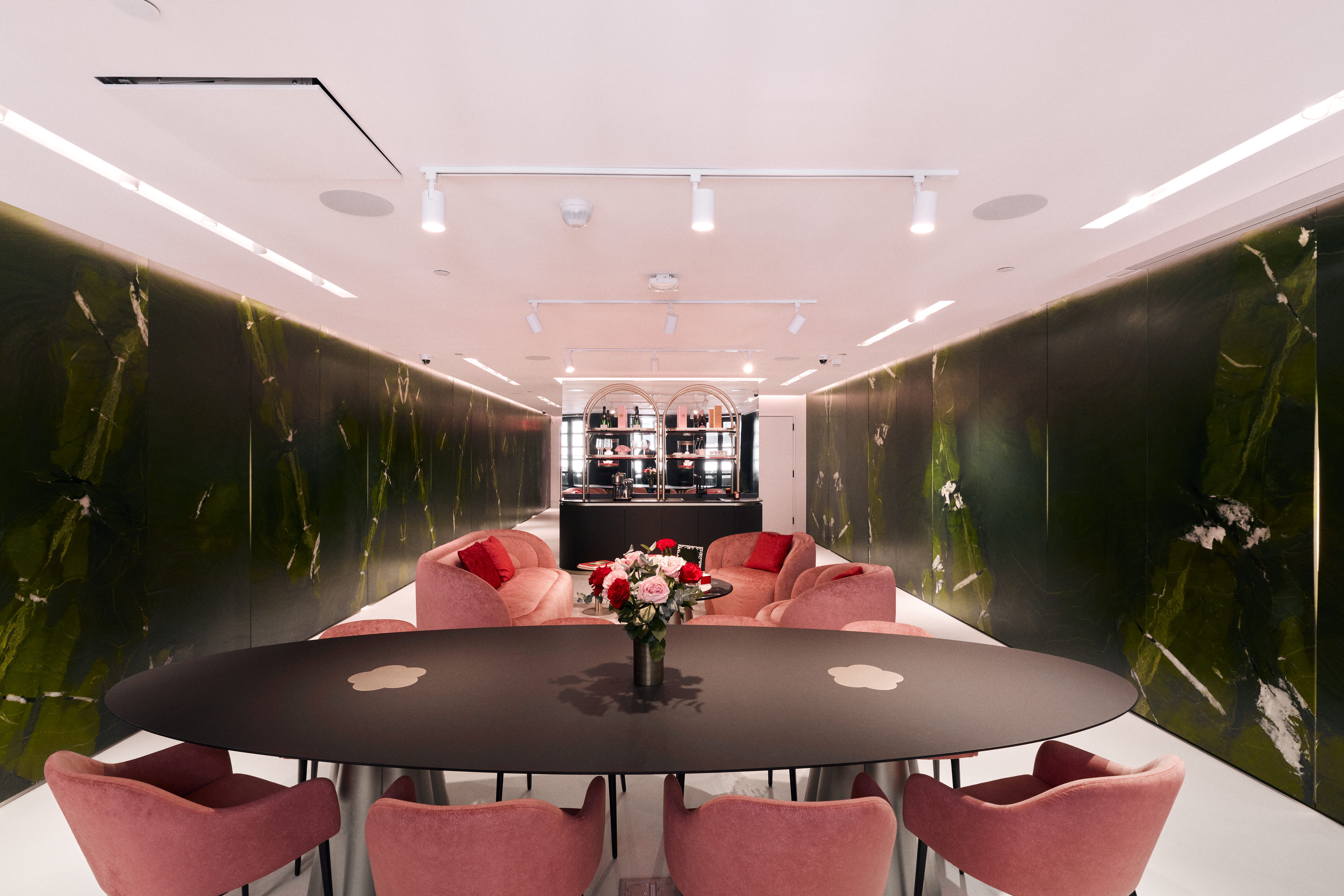 Modern dining area with pink chairs and a dark round table.
