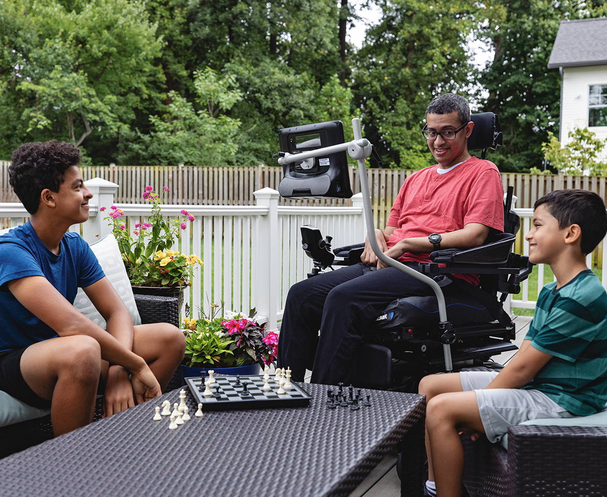 Mann mit ALS benutzt die Sprachausgabe in Communicator 5 von Tobii Dynavox, um seinen Söhnen beim Schachspiel zu helfen