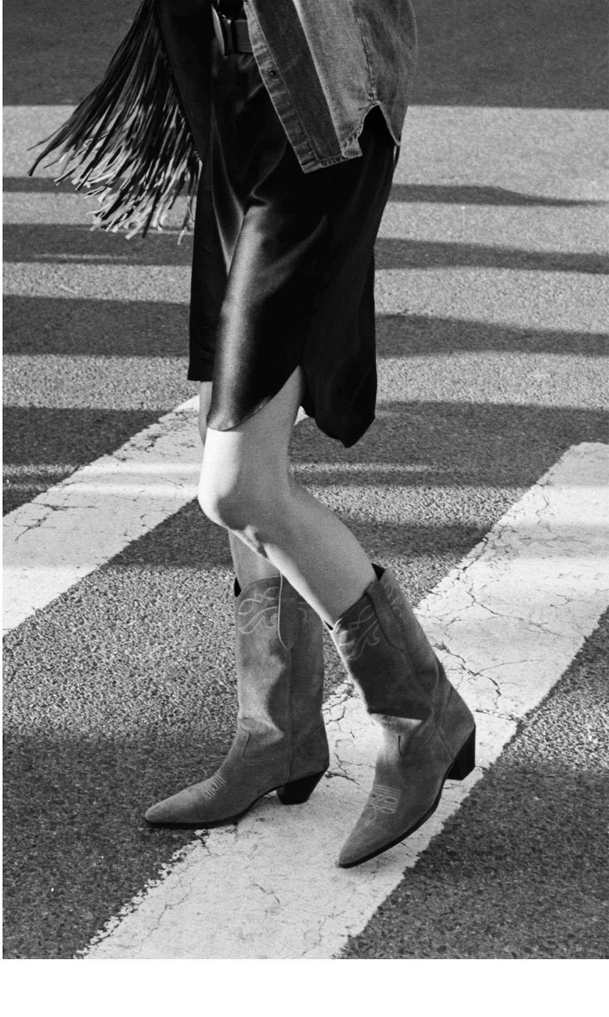 A person walking in cowboy boots on a crosswalk.