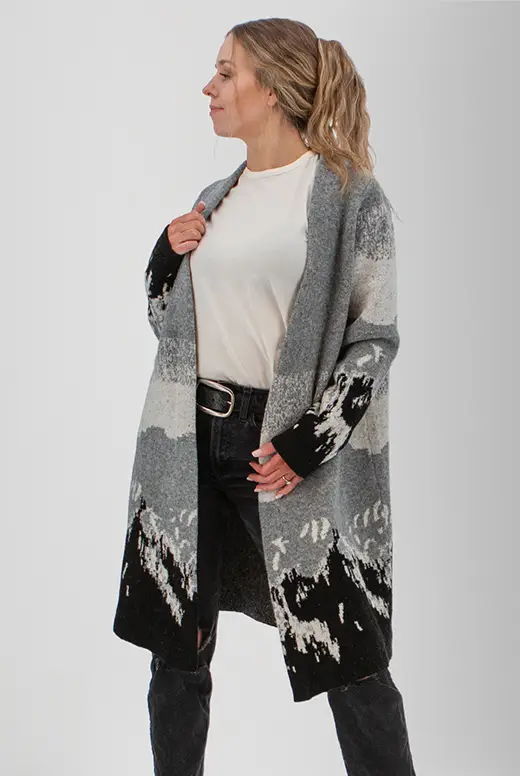 Woman wearing a patterned cardigan over a white shirt and black jeans.