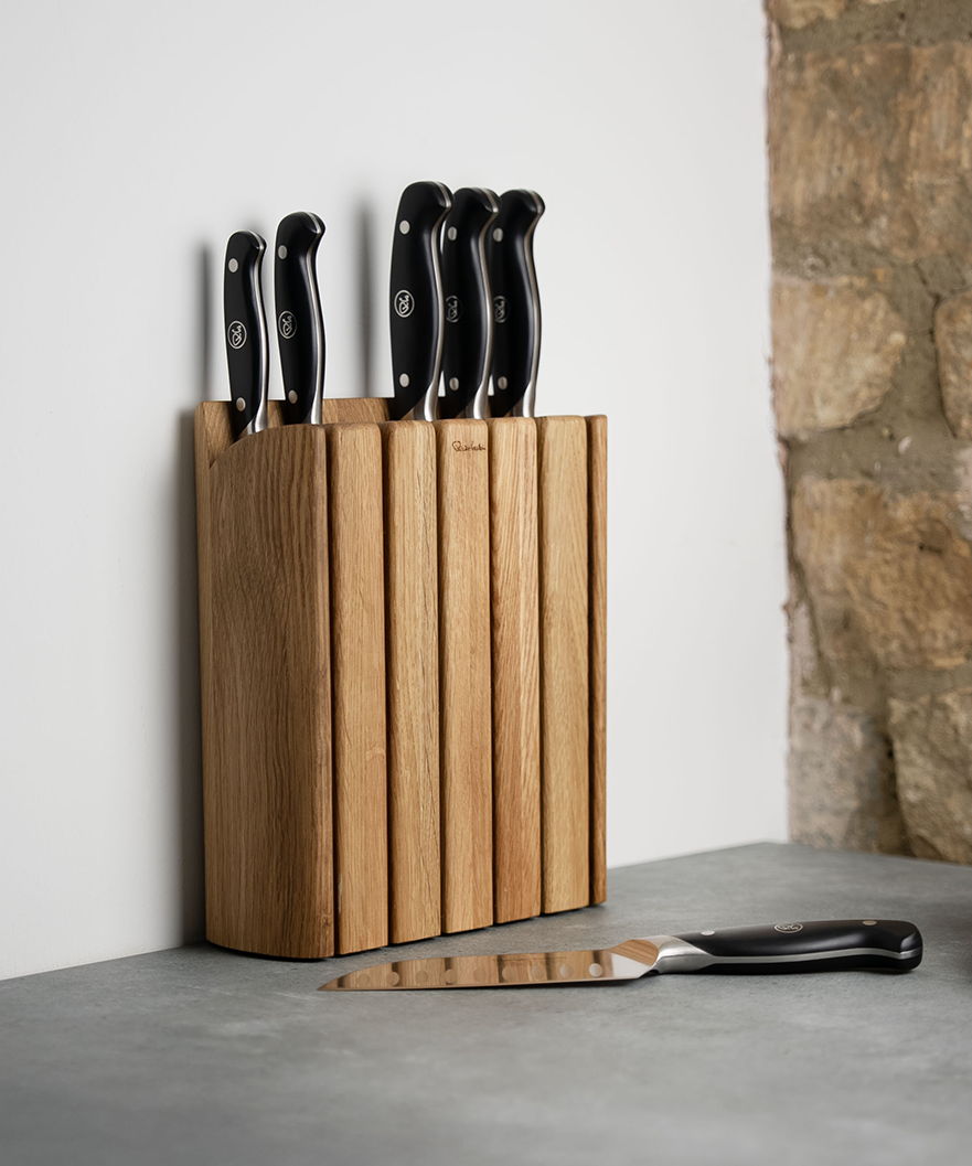 A wooden knife block with several knives and a cutting knife.