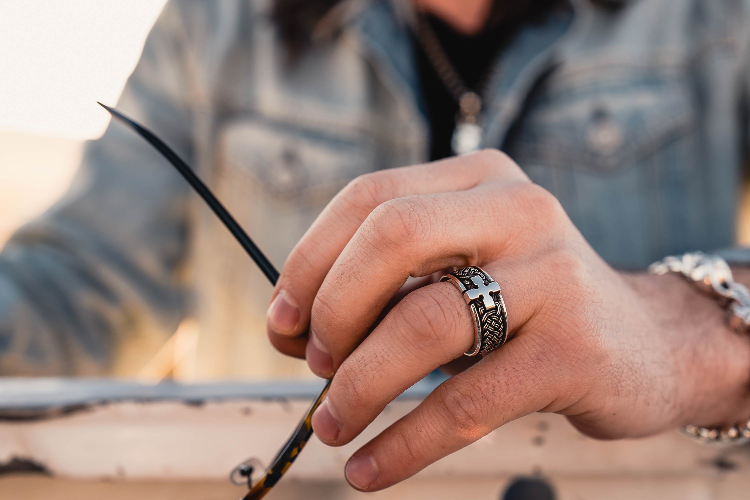 A Man Holding Sunglasses, Wearing the Joshua Cross Band Ring by NightRider Jewelry