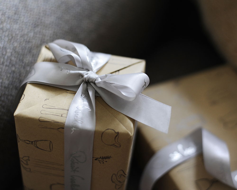 Gift-wrapped box with a silver ribbon on a textured surface.