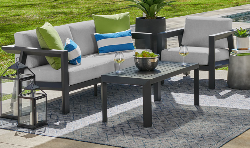Outdoor seating area with cushions, table, and decorative plants.