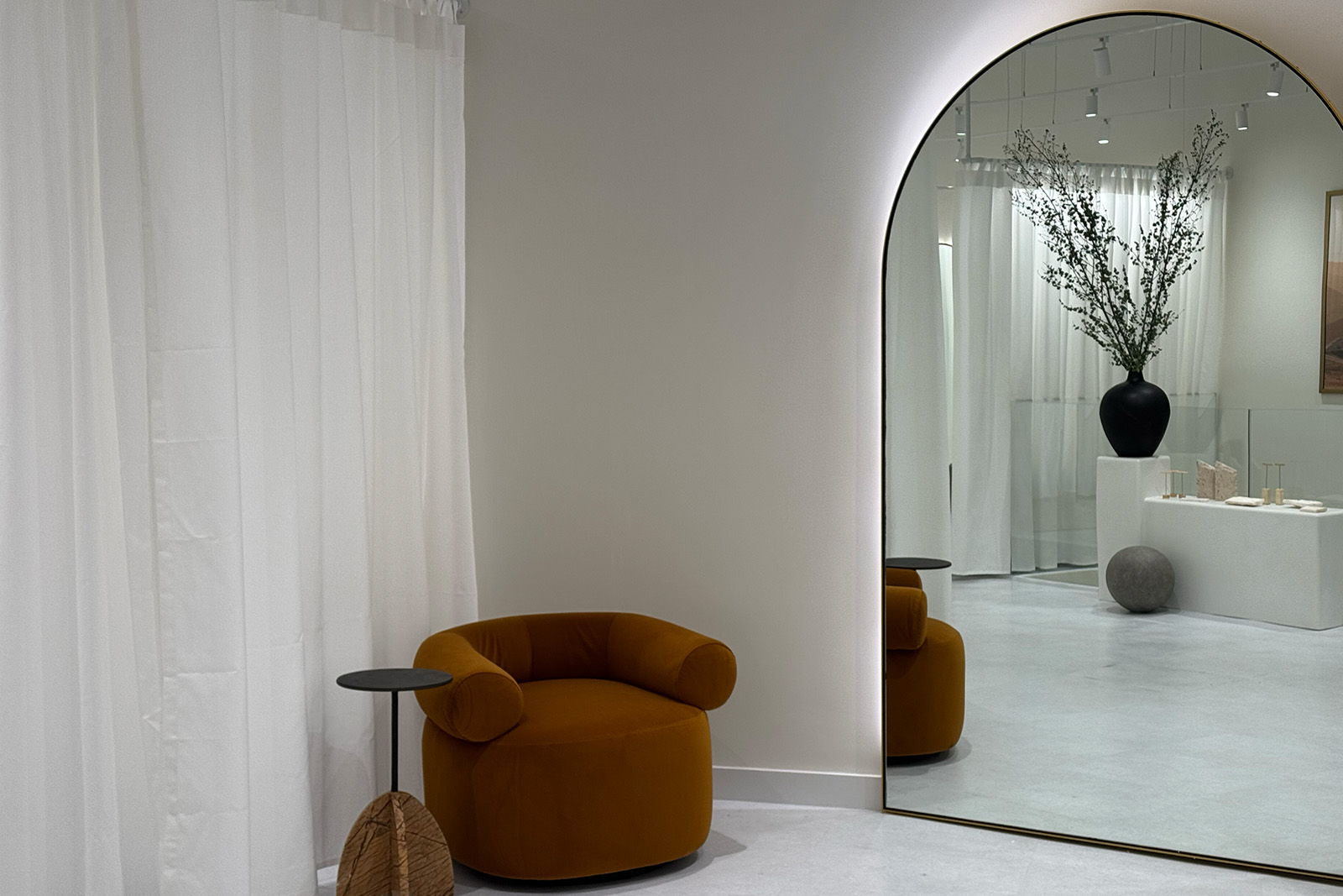 Cozy interior with a round mirror, orange chair, and decorative plants.