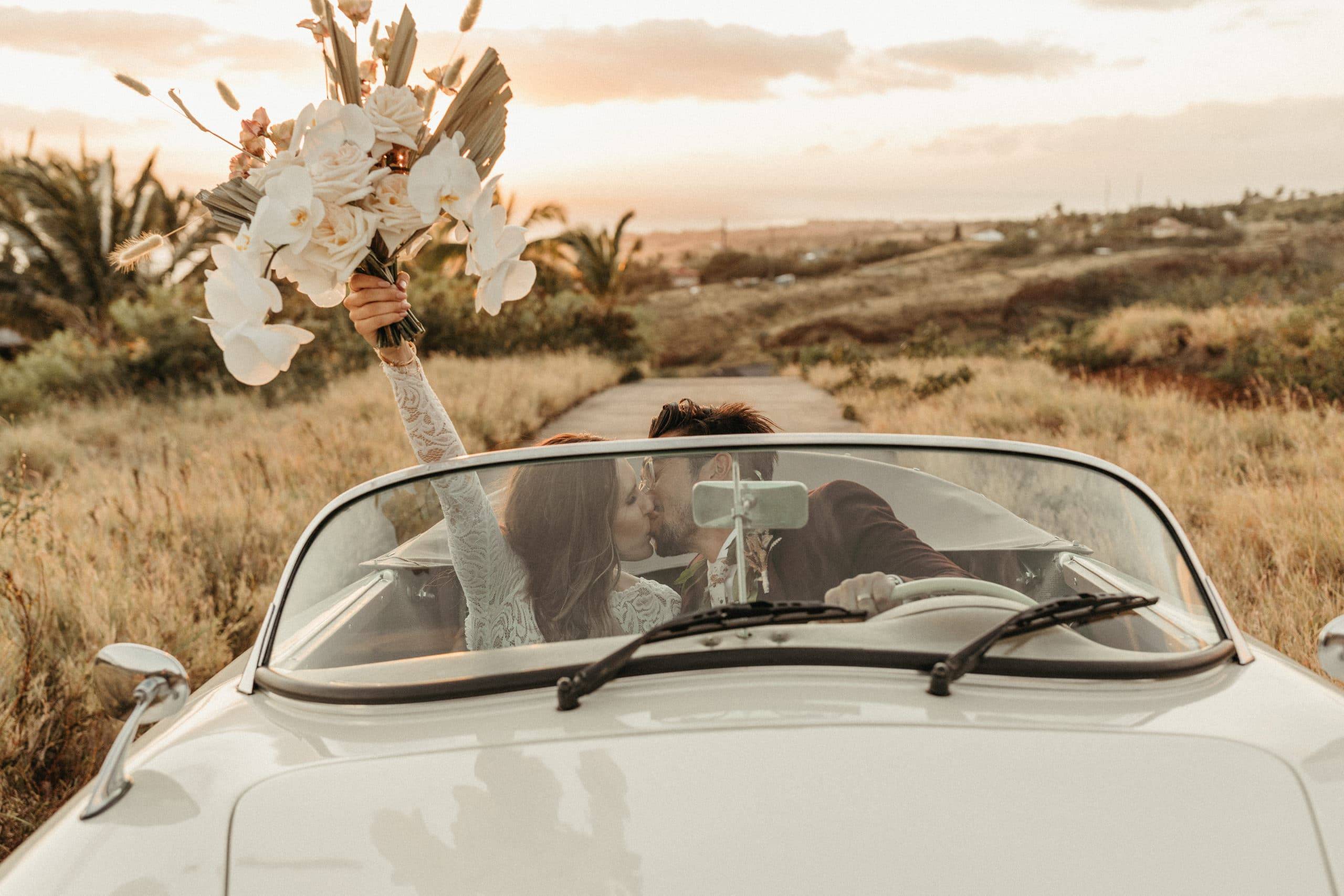 Newlyweds driving in a convertible kissing