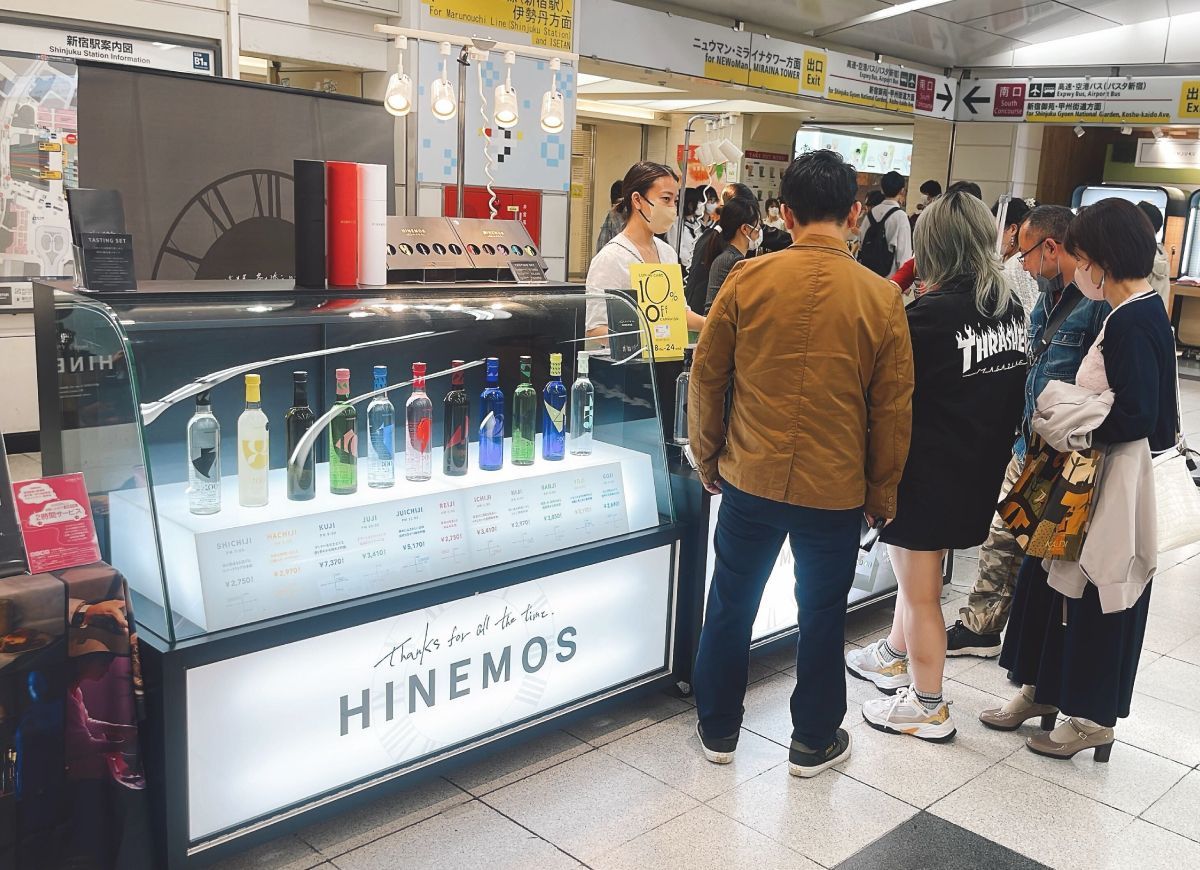 People gathered around a display of colorful bottles at a store.