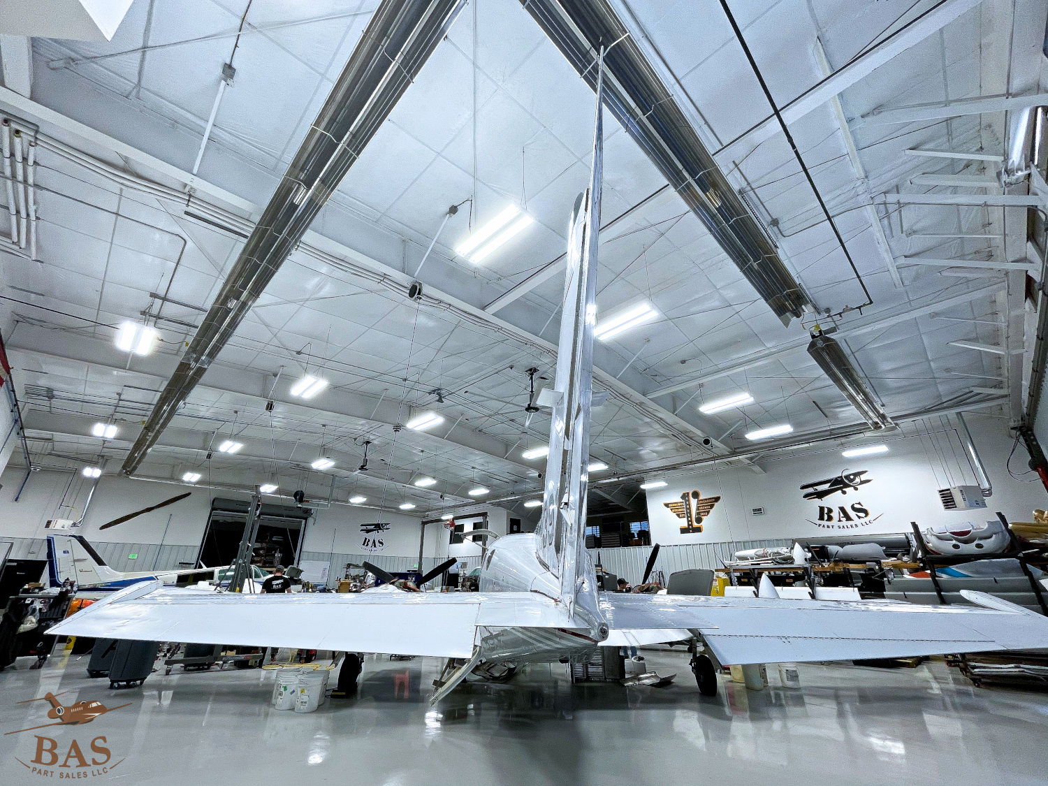 Aircraft inside a hangar with bright overhead lights and workspace.